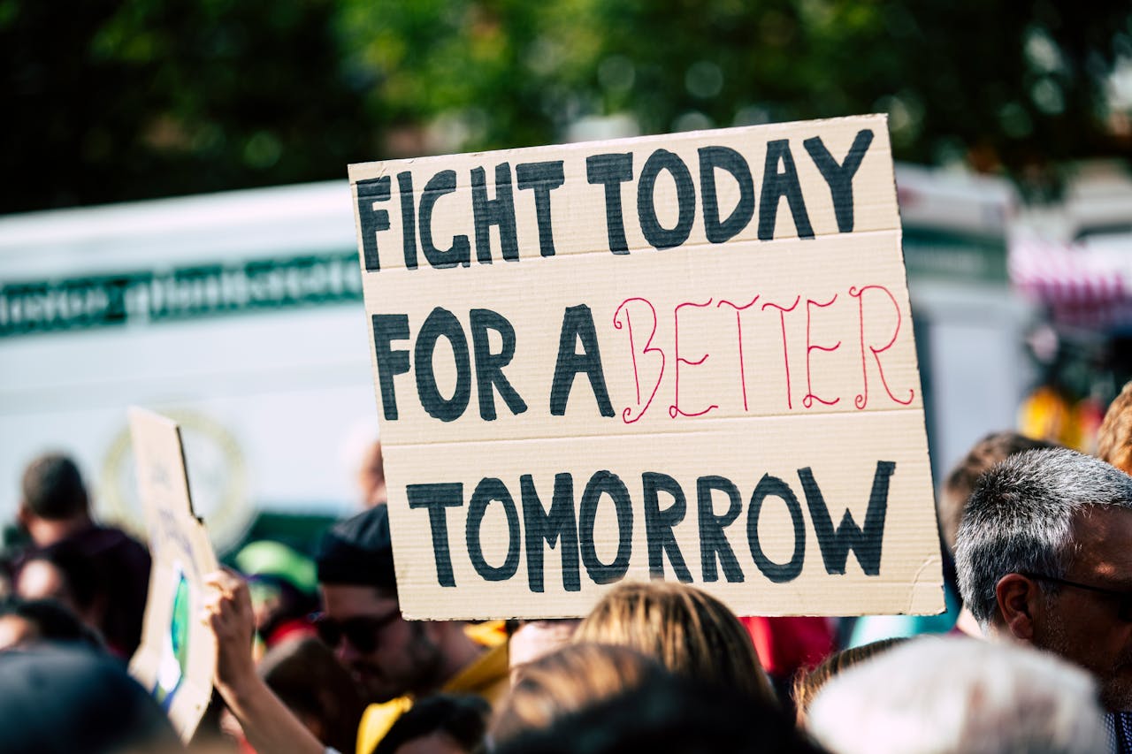 services-03 Crowd holding a protest sign with 'Fight Today for a Better Tomorrow', outdoors and during the day.