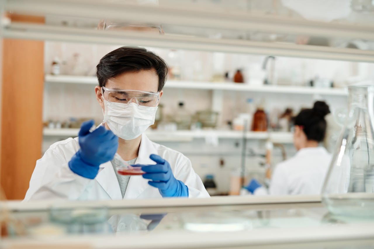 services-01 Researcher in a lab coat working on a scientific experiment with a petri dish and protective gear.