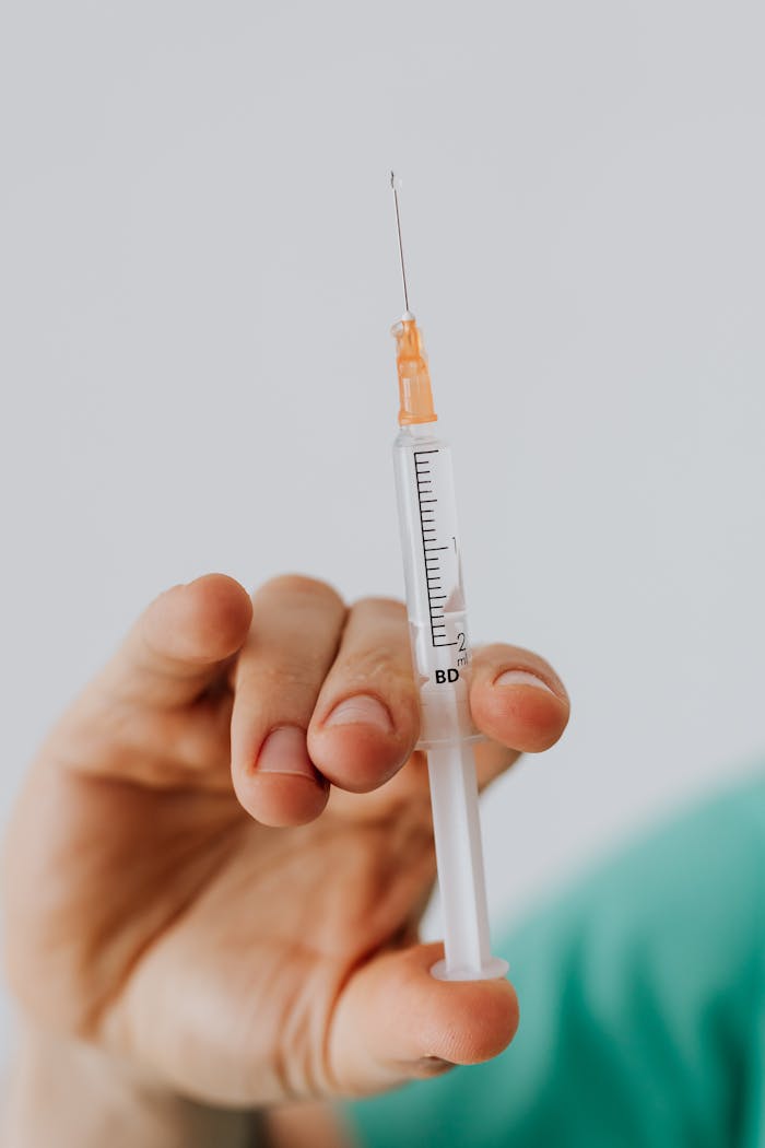 services-02 Detailed close-up shot of a hand holding a medical syringe against a neutral background.