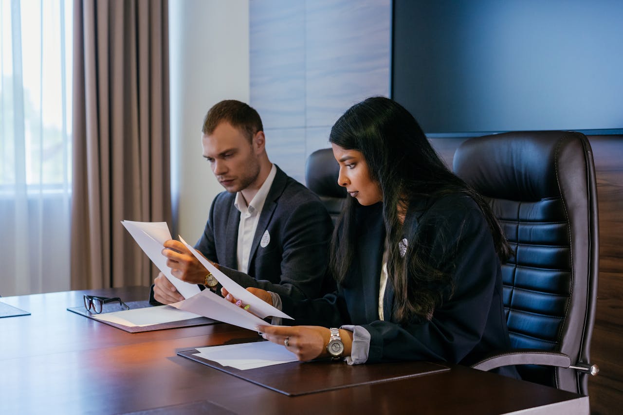 who-we-are Two business professionals in a conference room engaged in a meeting and document review.